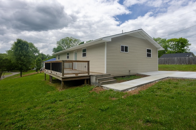 rear view of house featuring a deck and a lawn