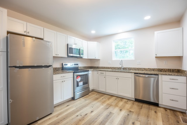 kitchen featuring stainless steel appliances, white cabinetry, light hardwood / wood-style floors, and sink