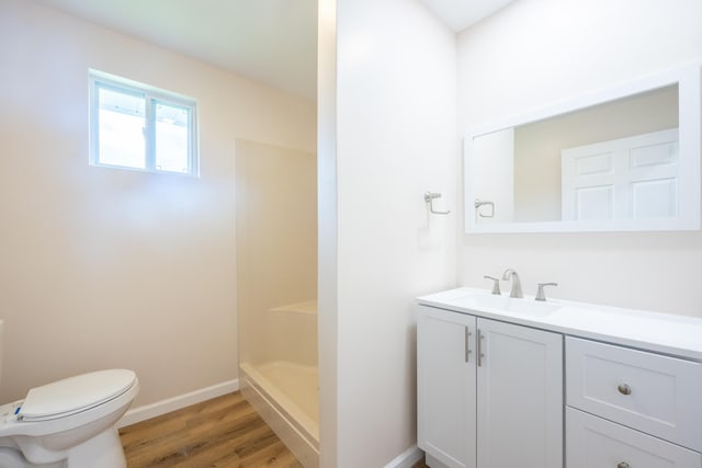 bathroom with wood-type flooring, vanity, toilet, and walk in shower