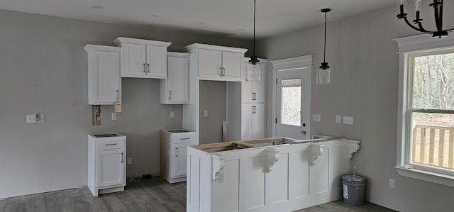 kitchen featuring white cabinetry, decorative light fixtures, and hardwood / wood-style floors