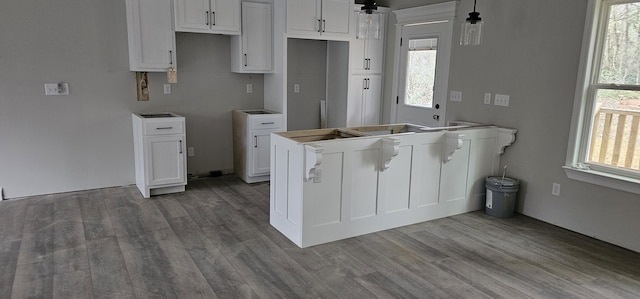 kitchen with hanging light fixtures, white cabinetry, and wood-type flooring