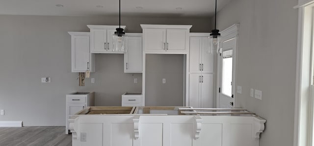 kitchen featuring pendant lighting, light hardwood / wood-style floors, and white cabinets