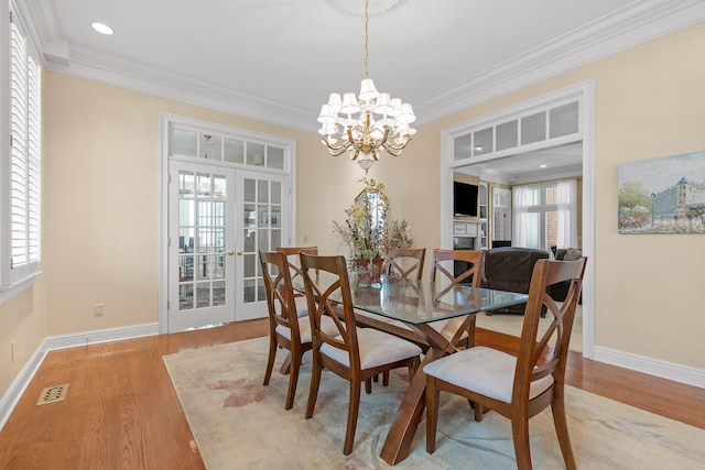 dining area featuring crown molding, light hardwood / wood-style flooring, a wealth of natural light, and french doors