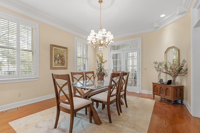 dining area with hardwood / wood-style flooring, a wealth of natural light, and ornamental molding