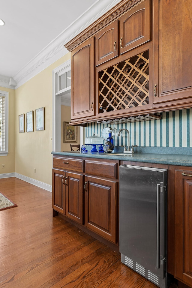 bar with stainless steel fridge, backsplash, dark hardwood / wood-style floors, and crown molding