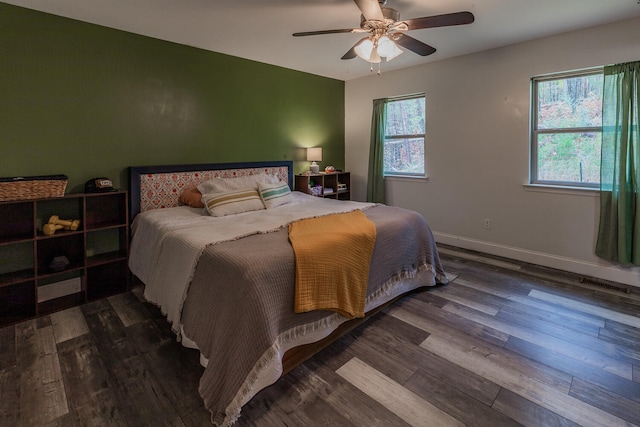 bedroom with ceiling fan, dark hardwood / wood-style flooring, and multiple windows