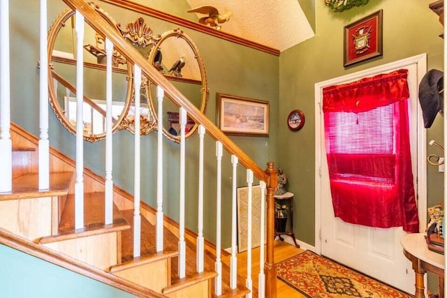 foyer entrance with hardwood / wood-style flooring, lofted ceiling, and ornamental molding