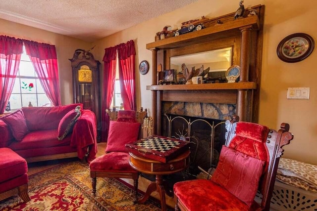 living room featuring a stone fireplace and a textured ceiling