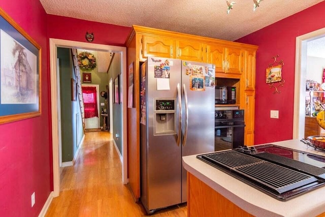 kitchen featuring black appliances, a textured ceiling, and light wood-type flooring