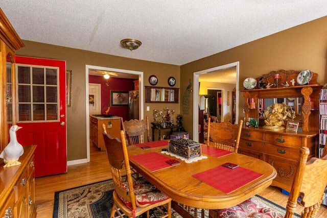 dining area featuring a textured ceiling, light wood-type flooring, and ceiling fan