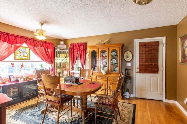 dining space with ceiling fan, a textured ceiling, and light hardwood / wood-style flooring