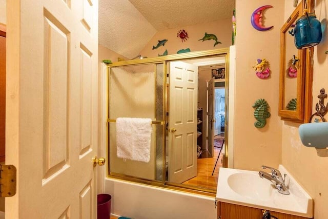 bathroom featuring combined bath / shower with glass door, vanity, a textured ceiling, and lofted ceiling