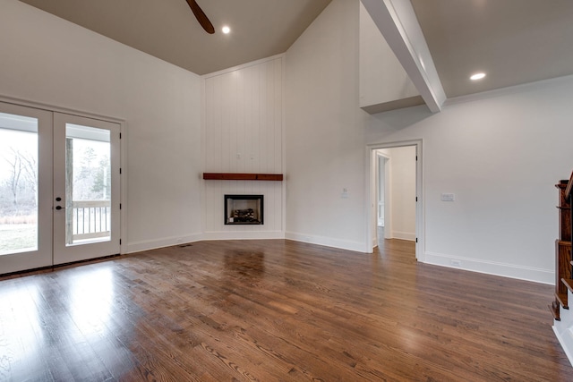 unfurnished living room featuring beam ceiling, ceiling fan, a large fireplace, french doors, and dark hardwood / wood-style floors