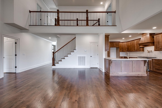 kitchen featuring premium range hood, dark hardwood / wood-style flooring, and a towering ceiling