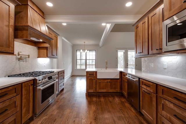 kitchen featuring backsplash, stainless steel appliances, sink, pendant lighting, and dark hardwood / wood-style floors