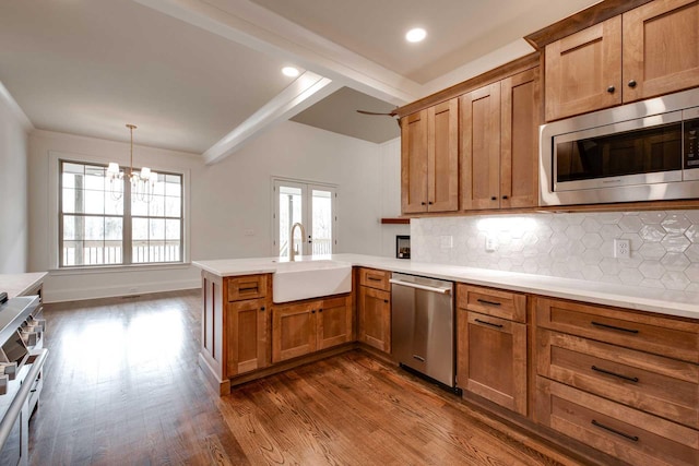 kitchen featuring kitchen peninsula, appliances with stainless steel finishes, a wealth of natural light, sink, and beam ceiling