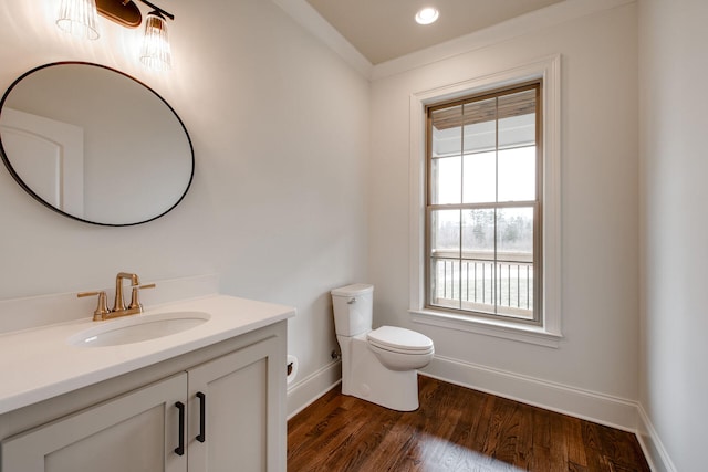 bathroom with toilet, vanity, ornamental molding, and hardwood / wood-style flooring