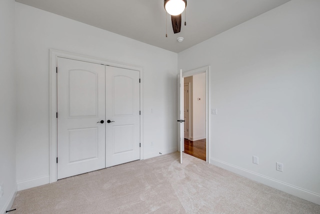 unfurnished bedroom with ceiling fan, a closet, and light colored carpet