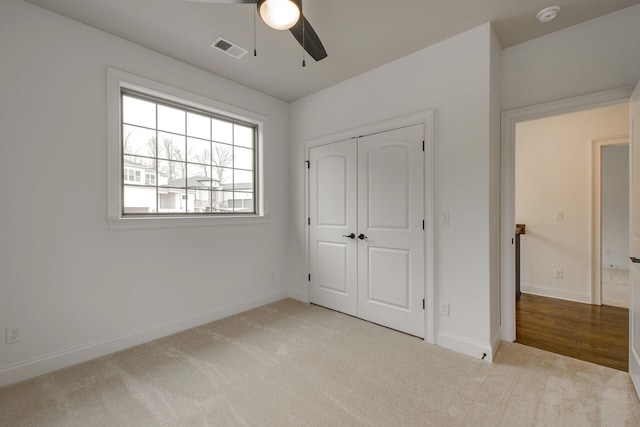 unfurnished bedroom with light carpet, a closet, and ceiling fan