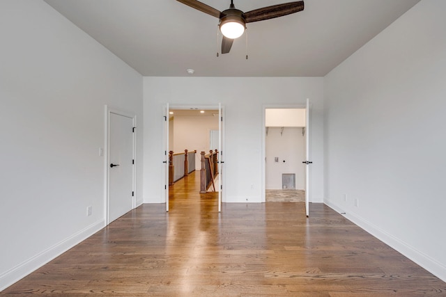 unfurnished bedroom with a closet, a spacious closet, hardwood / wood-style floors, and ceiling fan