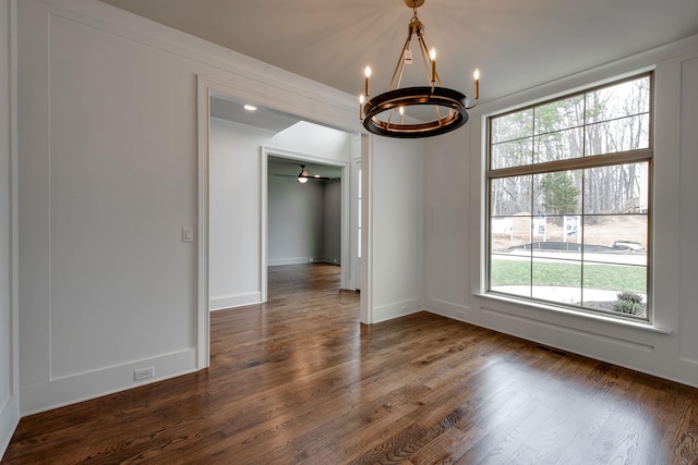 unfurnished dining area featuring ceiling fan with notable chandelier, dark hardwood / wood-style floors, and a wealth of natural light