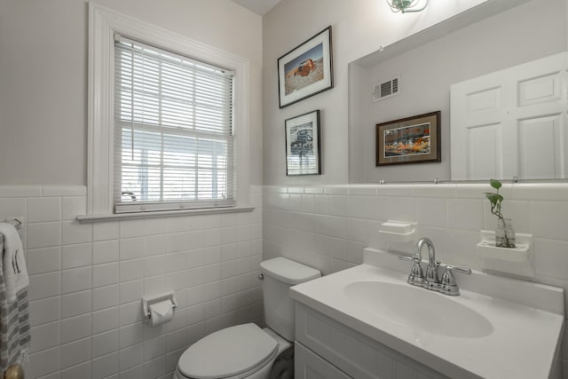 bathroom featuring vanity, toilet, and tile walls