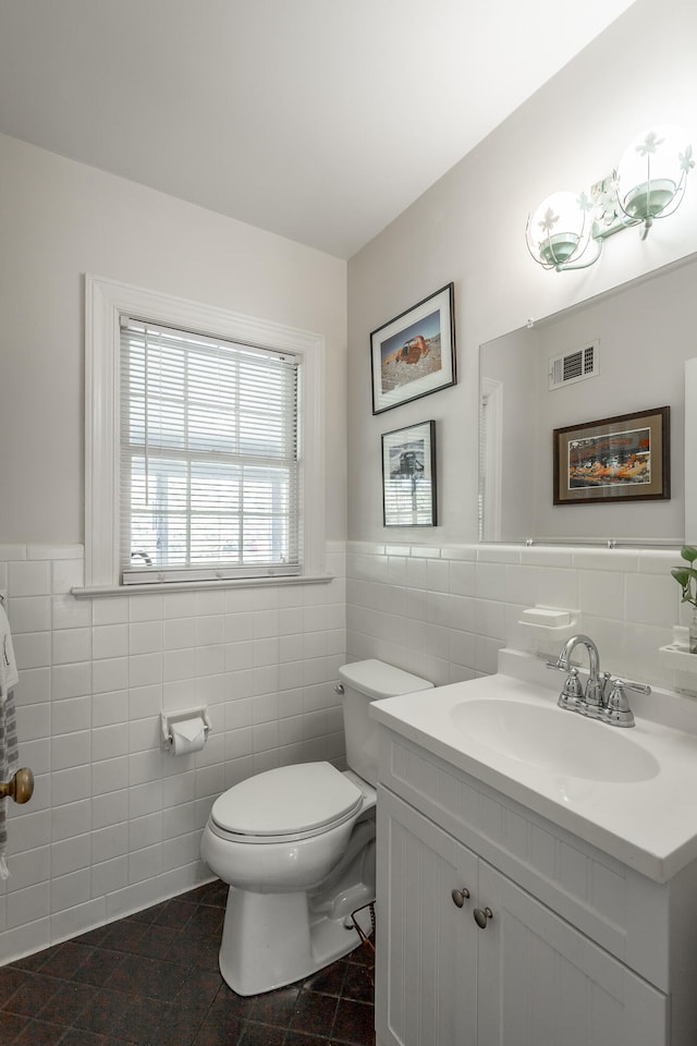 bathroom featuring tile patterned floors, vanity, toilet, and tile walls