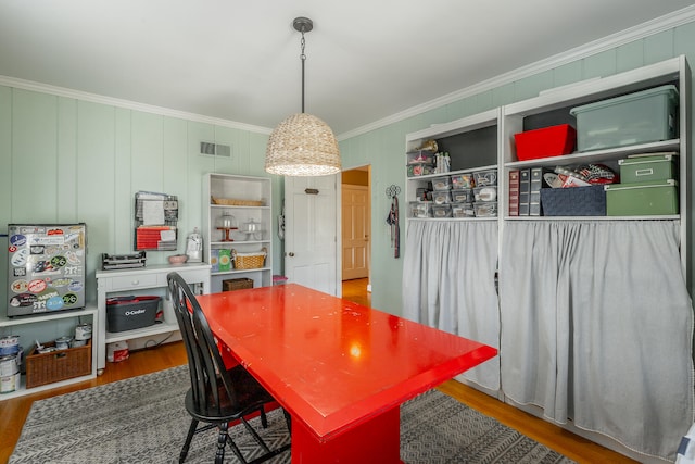 dining space featuring hardwood / wood-style floors and crown molding