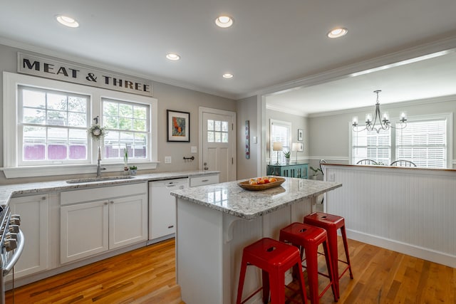 kitchen featuring white cabinetry, sink, light stone counters, light hardwood / wood-style flooring, and a kitchen island