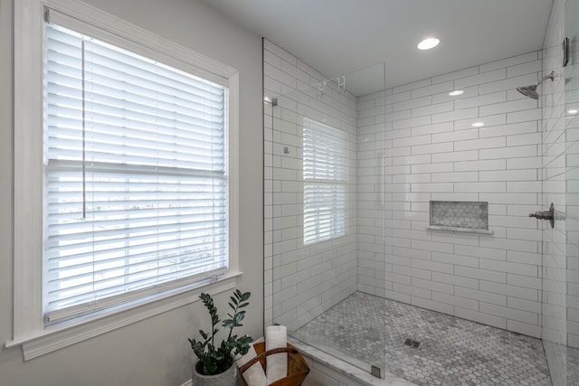 bathroom with a tile shower and a healthy amount of sunlight