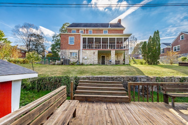 back of house featuring a sunroom, a deck, a lawn, and central air condition unit