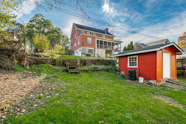 back of house with a lawn, a sunroom, and an outdoor structure