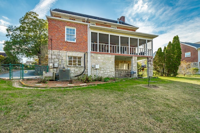 rear view of property with a lawn, a sunroom, and cooling unit