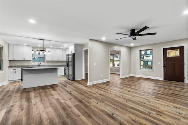 unfurnished living room featuring hardwood / wood-style floors, ceiling fan, and sink