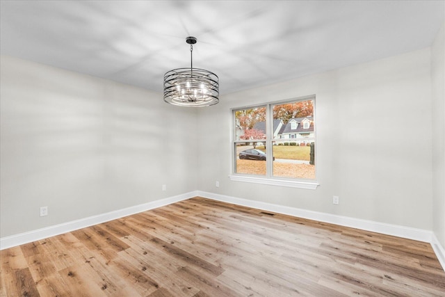 empty room featuring a chandelier and light hardwood / wood-style flooring