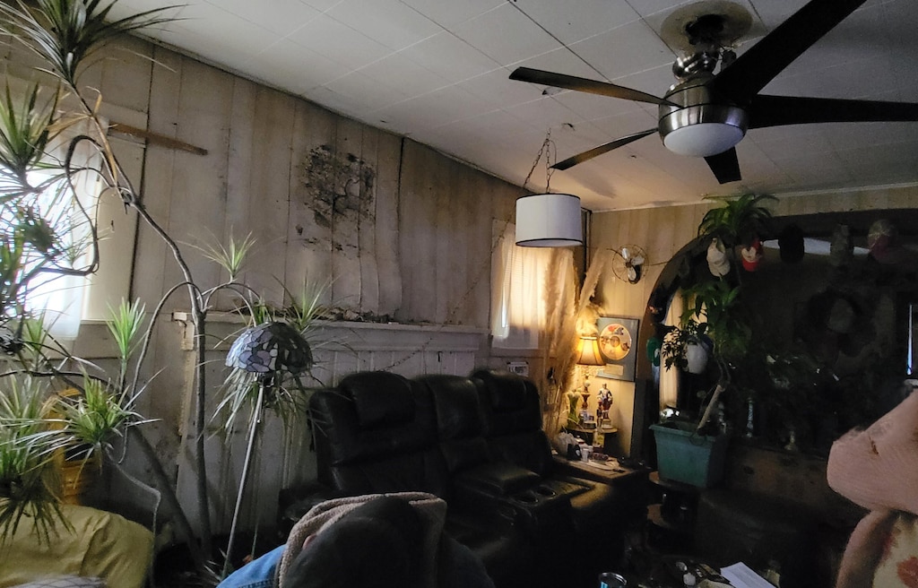 living room featuring ceiling fan and wooden walls