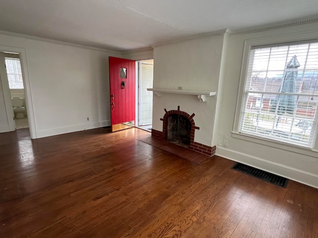 unfurnished living room with dark hardwood / wood-style flooring, crown molding, and a brick fireplace