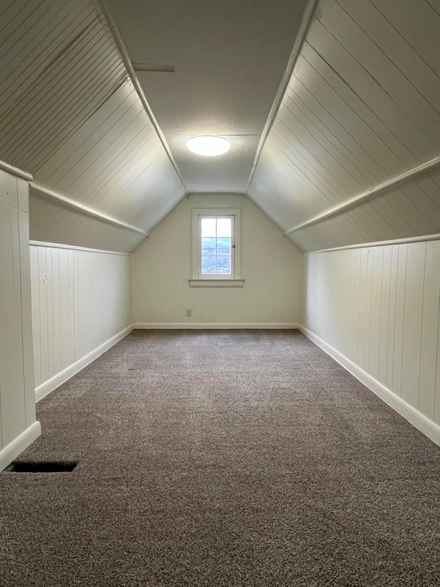 bonus room featuring carpet floors, wooden walls, and vaulted ceiling