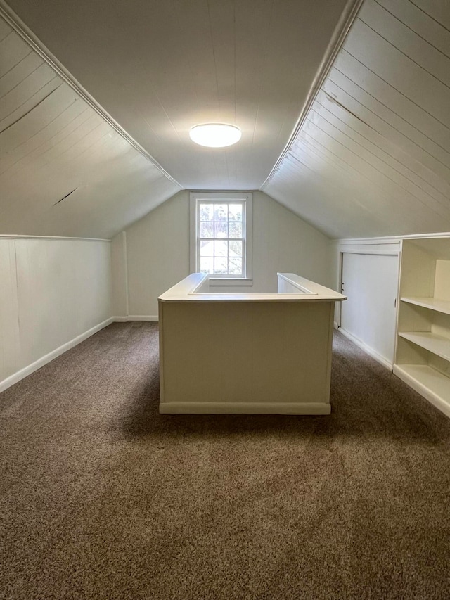 additional living space with dark colored carpet and vaulted ceiling