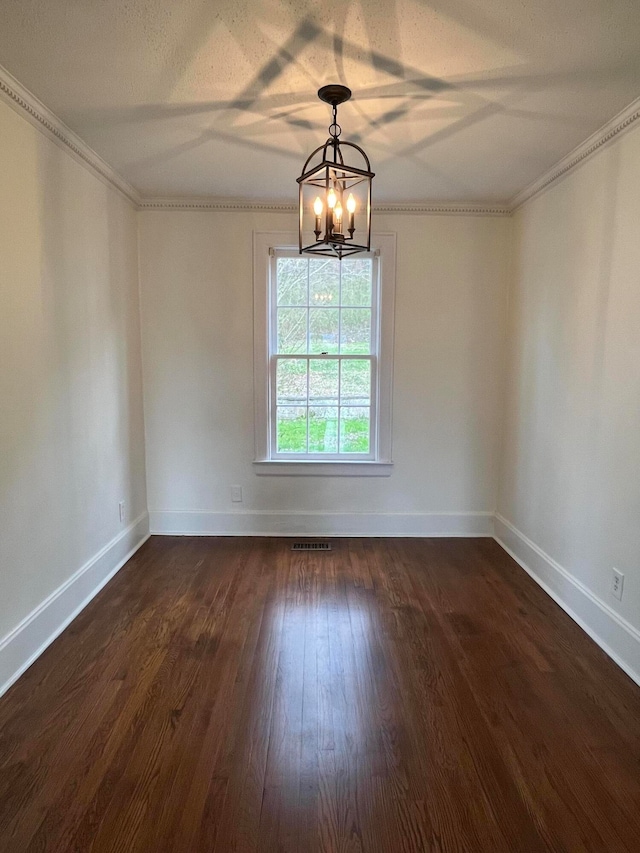 unfurnished room with a textured ceiling, crown molding, dark wood-type flooring, and an inviting chandelier