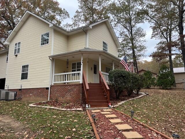 view of front of property featuring covered porch, central AC unit, and a front yard