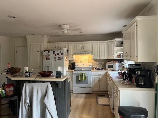 kitchen featuring white cabinets, a kitchen breakfast bar, white appliances, and sink