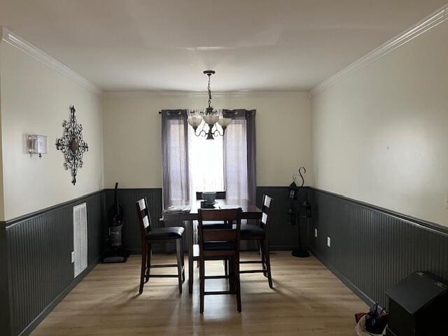 dining space with hardwood / wood-style flooring, an inviting chandelier, and ornamental molding