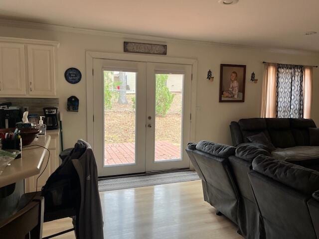 living room with light wood-type flooring, ornamental molding, and french doors