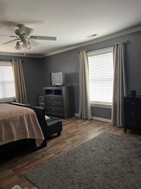 bedroom featuring ceiling fan, crown molding, and dark wood-type flooring