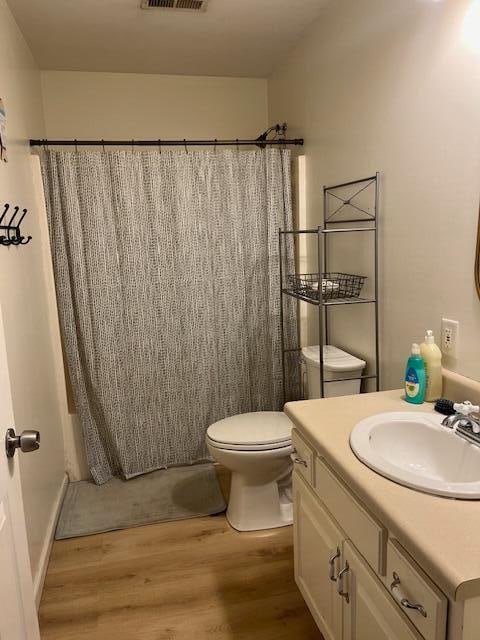 full bathroom featuring hardwood / wood-style floors, vanity, toilet, and shower / bathtub combination with curtain