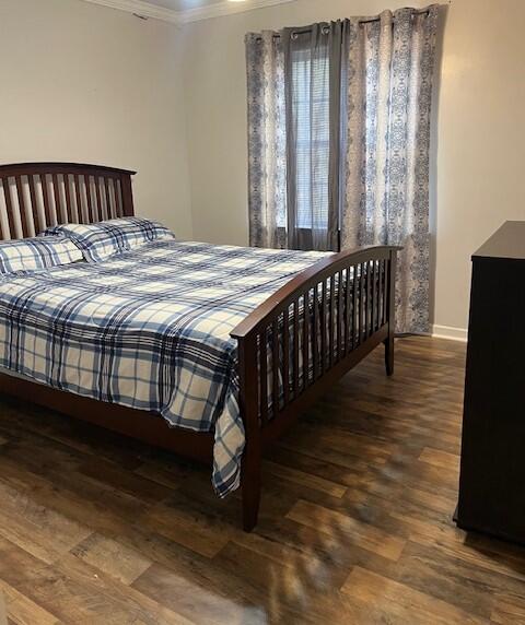 bedroom with crown molding and dark wood-type flooring