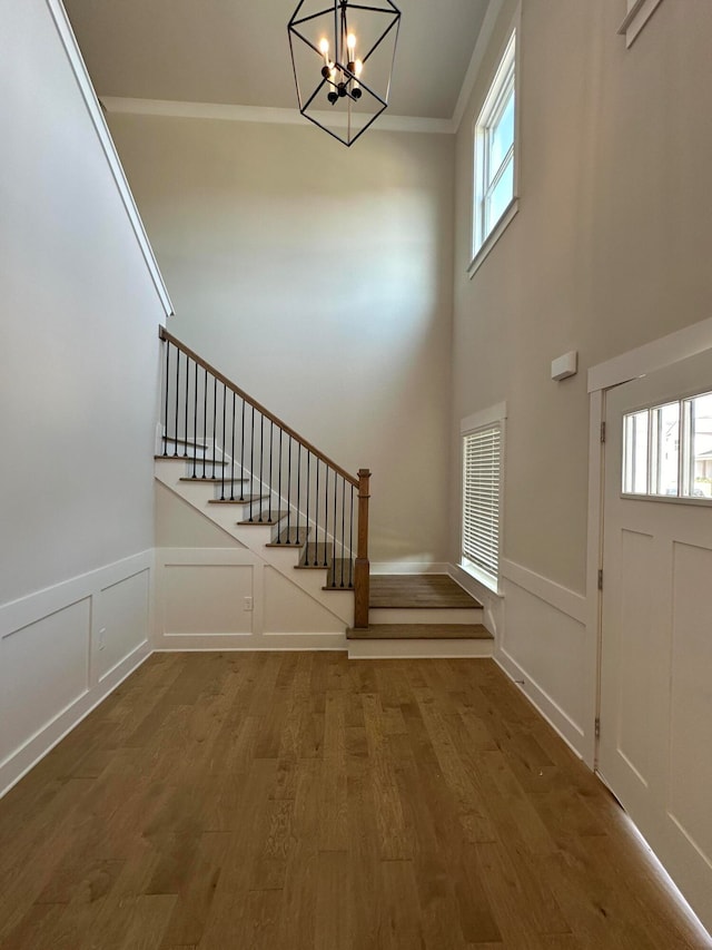 entrance foyer featuring wood-type flooring, ornamental molding, and an inviting chandelier