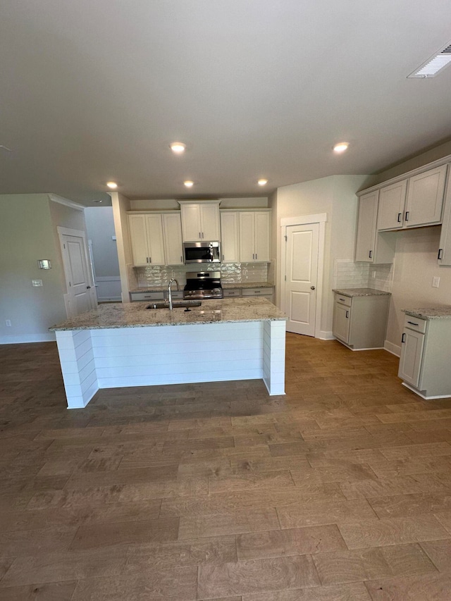 kitchen featuring a center island with sink, white cabinetry, sink, and appliances with stainless steel finishes