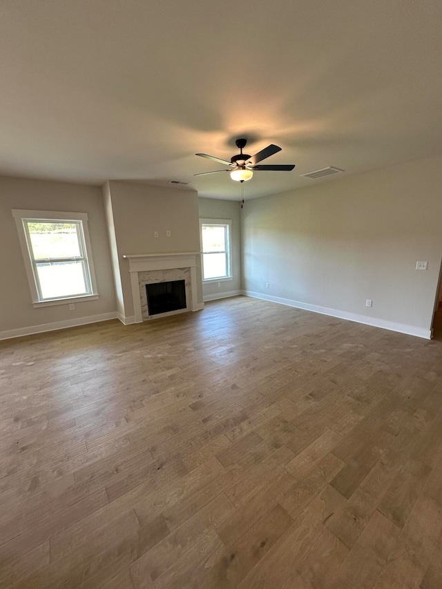 unfurnished living room with wood-type flooring, a wealth of natural light, and ceiling fan